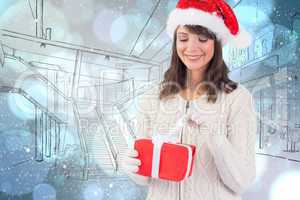 Composite image of festive brunette in santa hat opening a gift