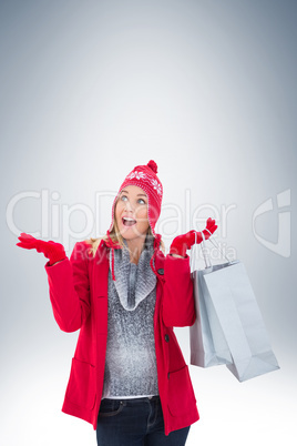 Happy blonde in winter clothes holding shopping bags