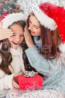 Composite image of festive mother and daughter on the couch with gift