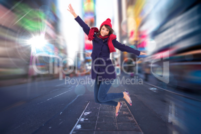 Composite image of woman in warm clothing jumping