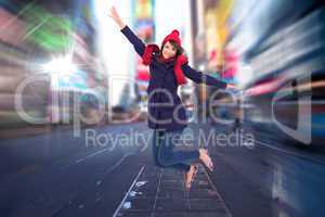 Composite image of woman in warm clothing jumping