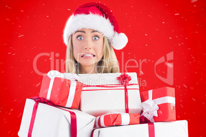 Composite image of festive blonde holding pile of gifts