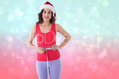 Composite image of festive athletic brunette measuring her waist