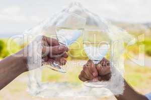 Composite image of couple clinking wine glasses outside