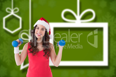 Composite image of festive fit brunette holding dumbbells