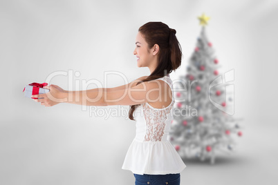 Composite image of festive brunette offering a gift