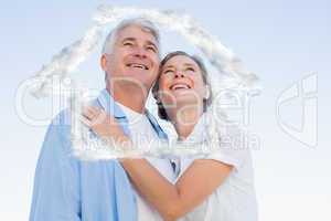 Composite image of happy casual couple embracing under blue sky