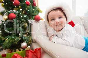 Composite image of cute baby boy on couch at christmas