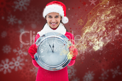 Composite image of festive brunette holding clock