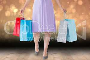 Composite image of mid section of woman holding shopping bags