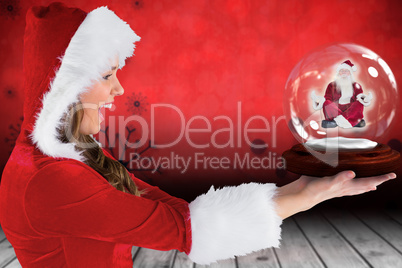 Composite image of sexy santa girl holding snow globe