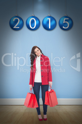 Composite image of smiling brunette in winter clothes holding sh