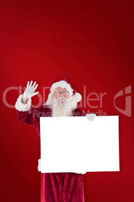 Composite image of santa holds a sign and is waving