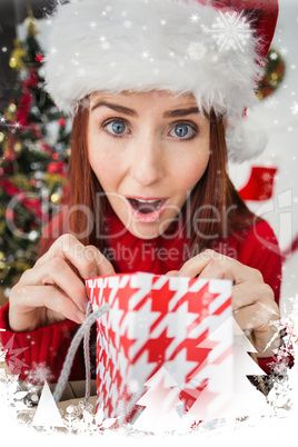 Composite image of festive redhead opening christmas gift