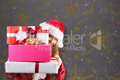 Composite image of festive redhead holding pile of gifts