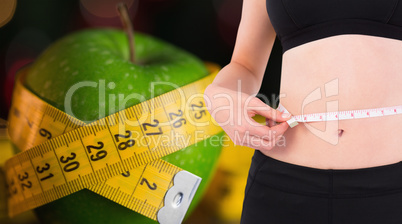 Composite image of fit woman measuring her waist