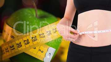 Composite image of fit woman measuring her waist