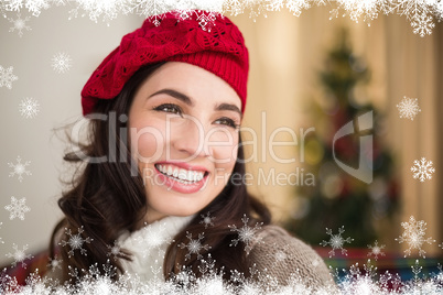 Composite image of smiling brunette on the couch at christmas