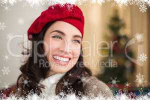 Composite image of smiling brunette on the couch at christmas