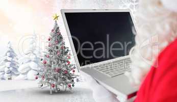 Composite image of father christmas using his laptop