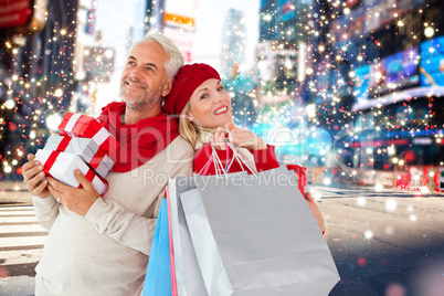 Composite image of happy festive couple with gifts and bags