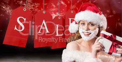 Composite image of festive redhead in foam beard holding gift