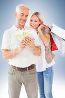 Composite image of happy couple with shopping bags and cash