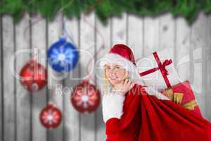 Composite image of festive blonde carrying sack of presents