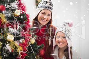 Composite image of mother and daughter decorating christmas tree