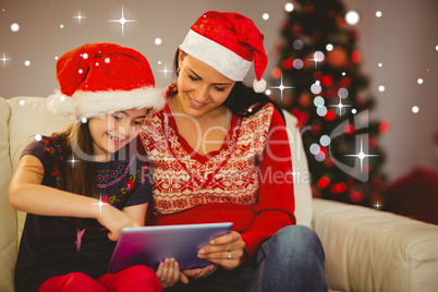 Composite image of festive mother and daughter using tablet