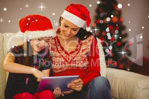 Composite image of festive mother and daughter using tablet