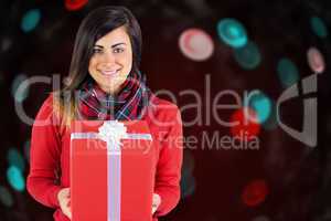 Composite image of smiling brunette holding a gift with white bow