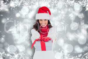 Composite image of festive brunette in santa hat giving gift