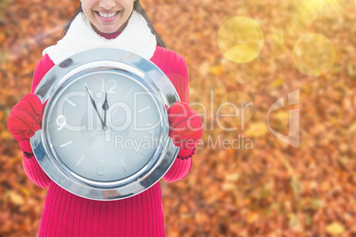 Composite image of festive brunette holding clock