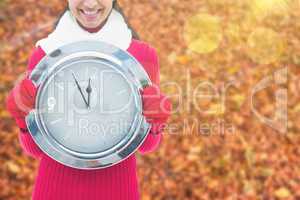 Composite image of festive brunette holding clock