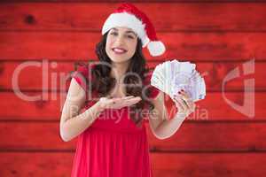 Composite image of festive brunette presenting her cash