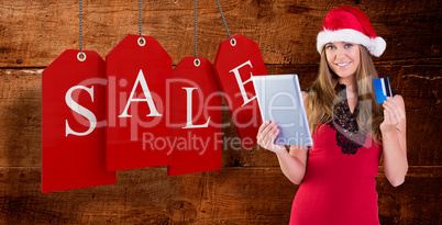 Composite image of festive blonde shopping online with tablet