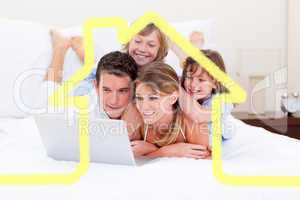 Composite image of loving family looking at a laptop lying down