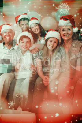 Composite image of extended family in christmas hats with gift b