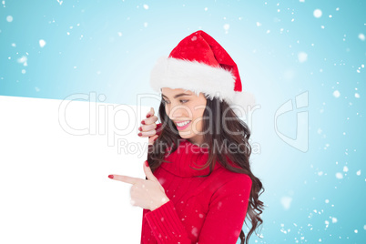 Composite image of beauty brunette in santa hat pointing white p