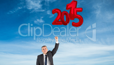 Composite image of mature businessman cheering with arm up