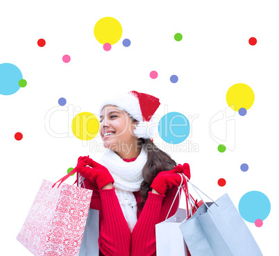 Composite image of festive brunette holding shopping bags