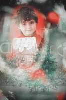 Composite image of festive little boy holding gingerbread house