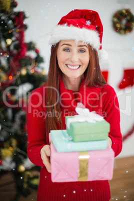 Composite image of festive redhead holding christmas gifts