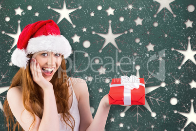 Composite image of festive redhead holding a gift