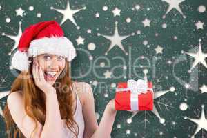 Composite image of festive redhead holding a gift