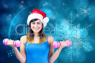 Composite image of festive fit brunette holding dumbbells