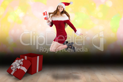 Composite image of festive redhead jumping with gift