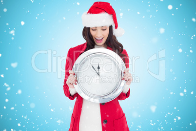 Composite image of excited brunette holding a clock