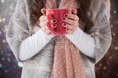 Composite image of woman in winter clothes holding a hot drink